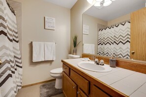 A bathroom with a white sink, wooden vanity, a mirror, and a shower curtain with a zigzag pattern. - Heart of Boise*Simplot sports complex*Pool Table (Boise)