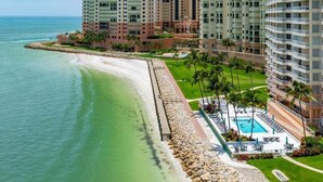 Un hotel sulla spiaggia con diversi edifici alti, una piscina e la spiaggia.