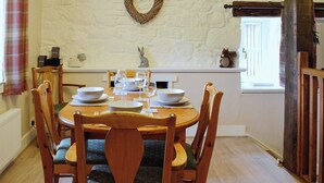 A dining room with a round wooden table set for four, surrounded by wooden chairs with cushioned seats.
