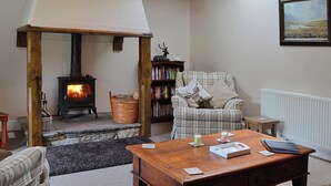 A cozy living room with a fireplace, a plaid sofa, a coffee table, and a bookshelf.