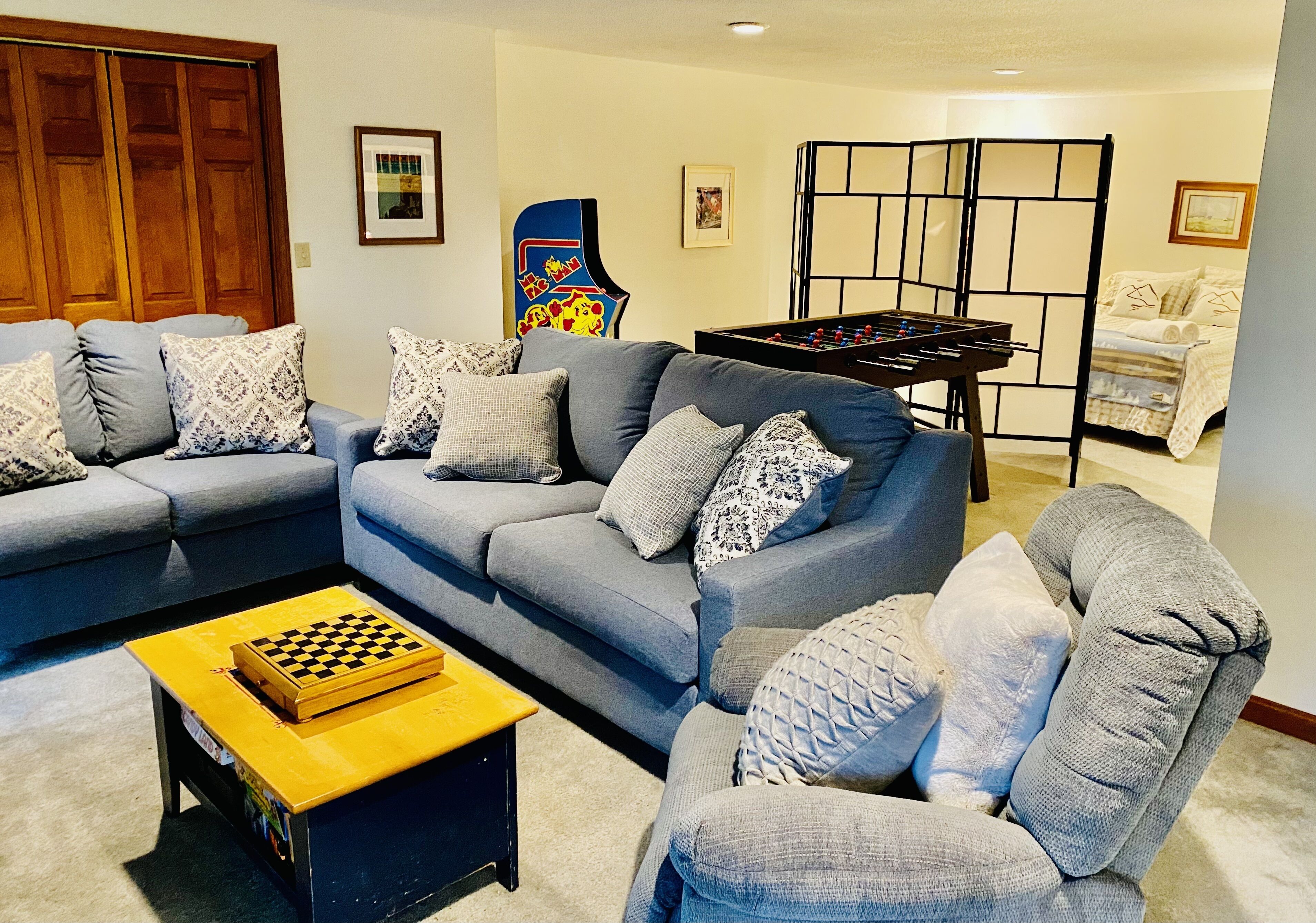 Uma sala de estar com um conjunto de sofás, uma mesa de futebol e uma mesa de xadrez.