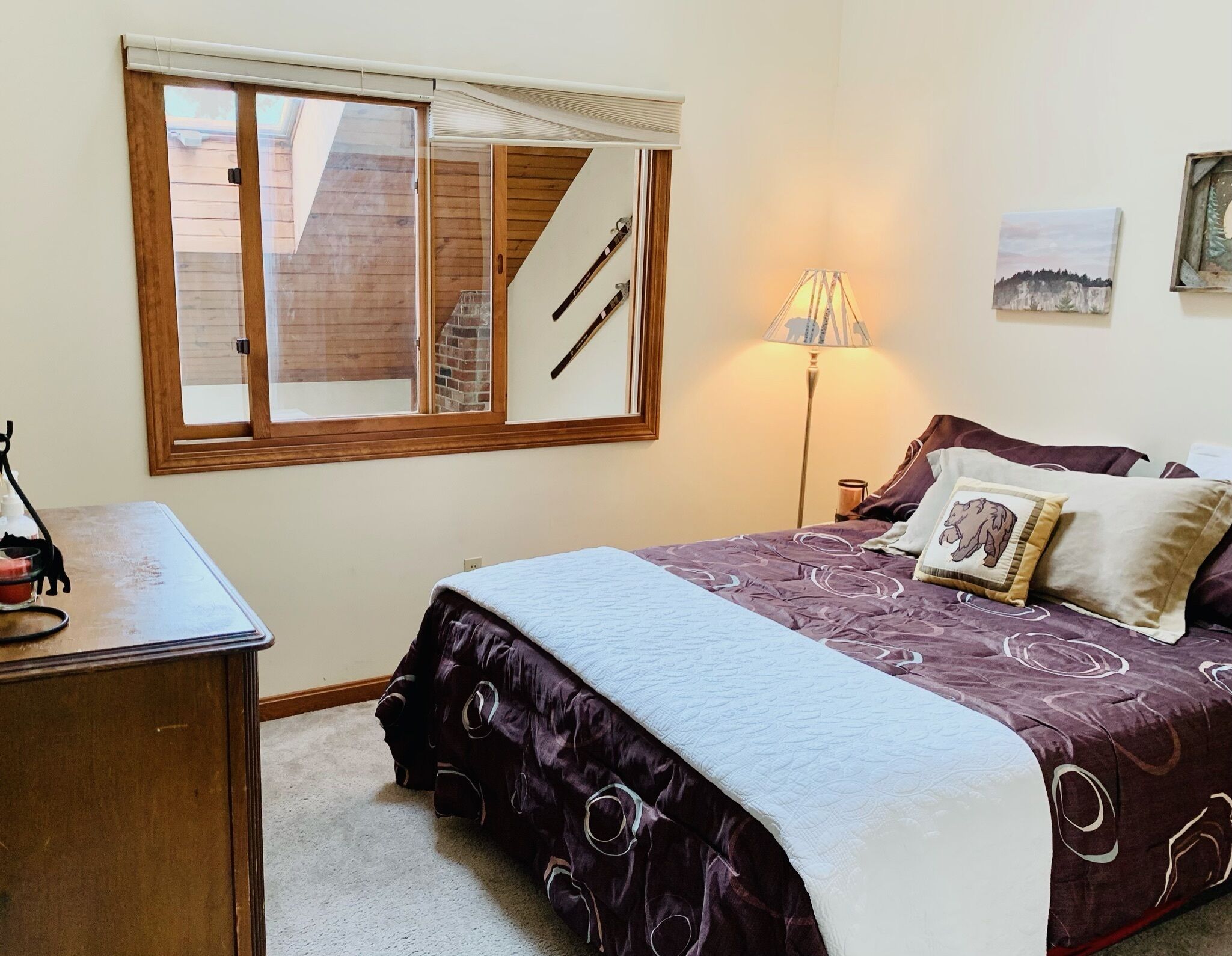 Une chambre à coucher avec un lit, un bureau, une lampe et une fenêtre avec des stores.