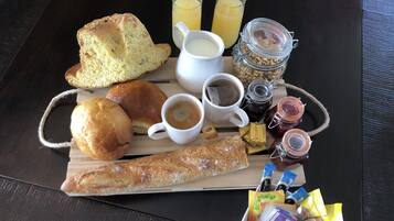 A breakfast tray with bread, pastries, coffee, juice, and condiments.
