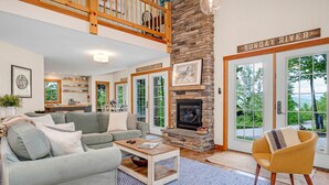 A spacious living room with a stone fireplace, a sofa, a coffee table, and a view of the outdoors.
