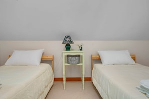 Habitación doble con dos camas, una mesita con lámpara y un estante en la pared.