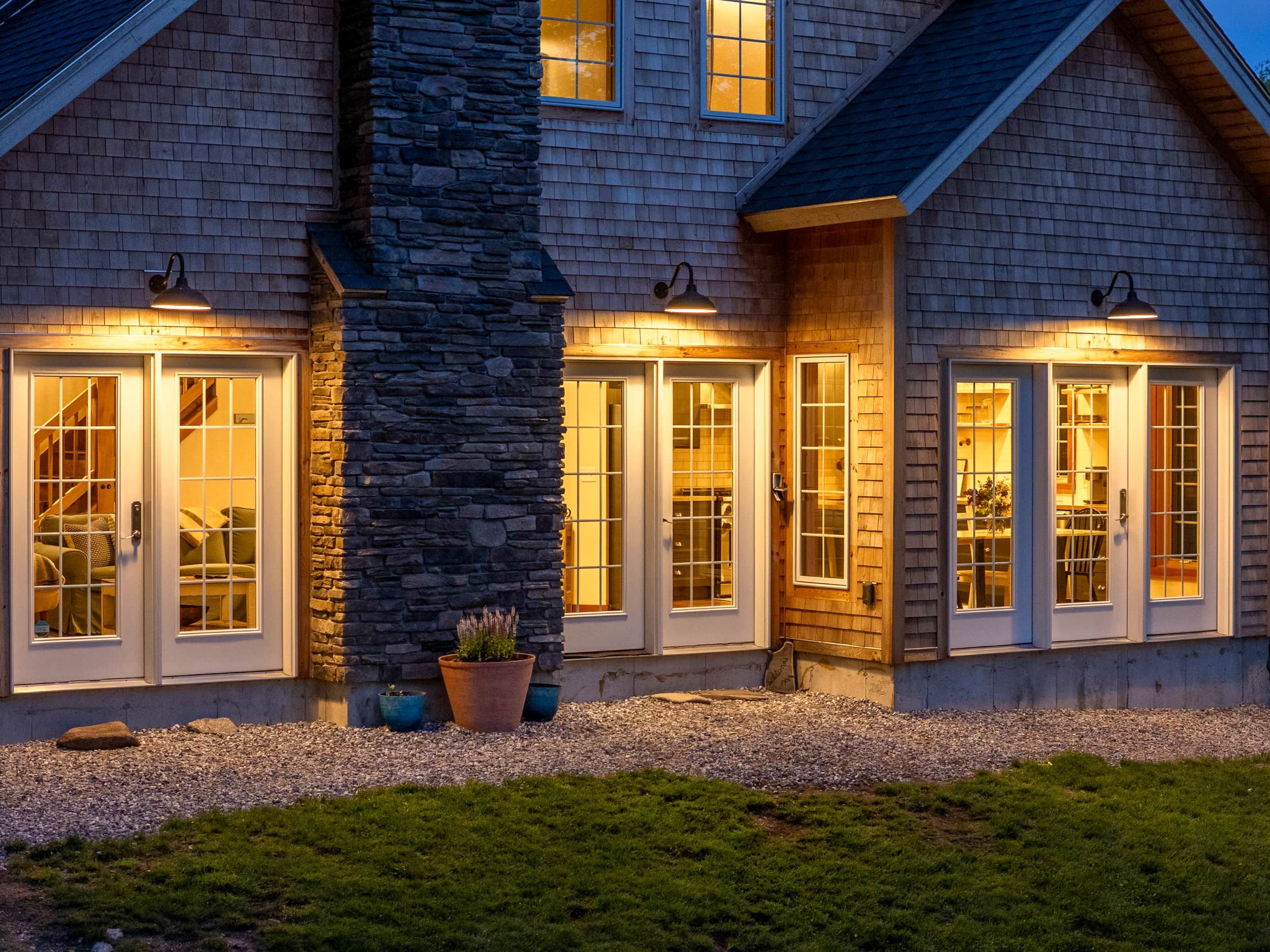 A house with a stone column, multiple entry doors, and a gravel driveway.