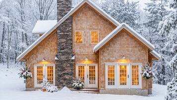 Cozy winter exterior of Three Peaks Cabin tucked in a snow-covered forest.
