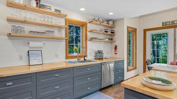 A modern kitchen with wooden shelves, a dishwasher, and a welcome sign.
