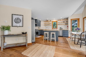 A modern kitchen with wooden flooring, a central island, and built-in shelves.