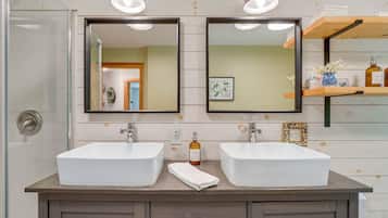 A bathroom with two white sinks, a towel, and a shelf with toiletries.