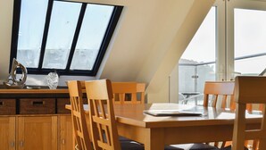A dining area with a high ceiling and skylight, wooden furniture, and a view through the windows. - 3 bedroom accommodation in Buckley St (Buckley St)
