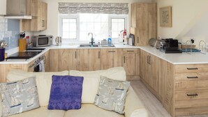 A modern kitchen with wooden cabinets, a microwave, a stove, and a sink. - 3 bedroom accommodation in Buckley St (Buckley St)