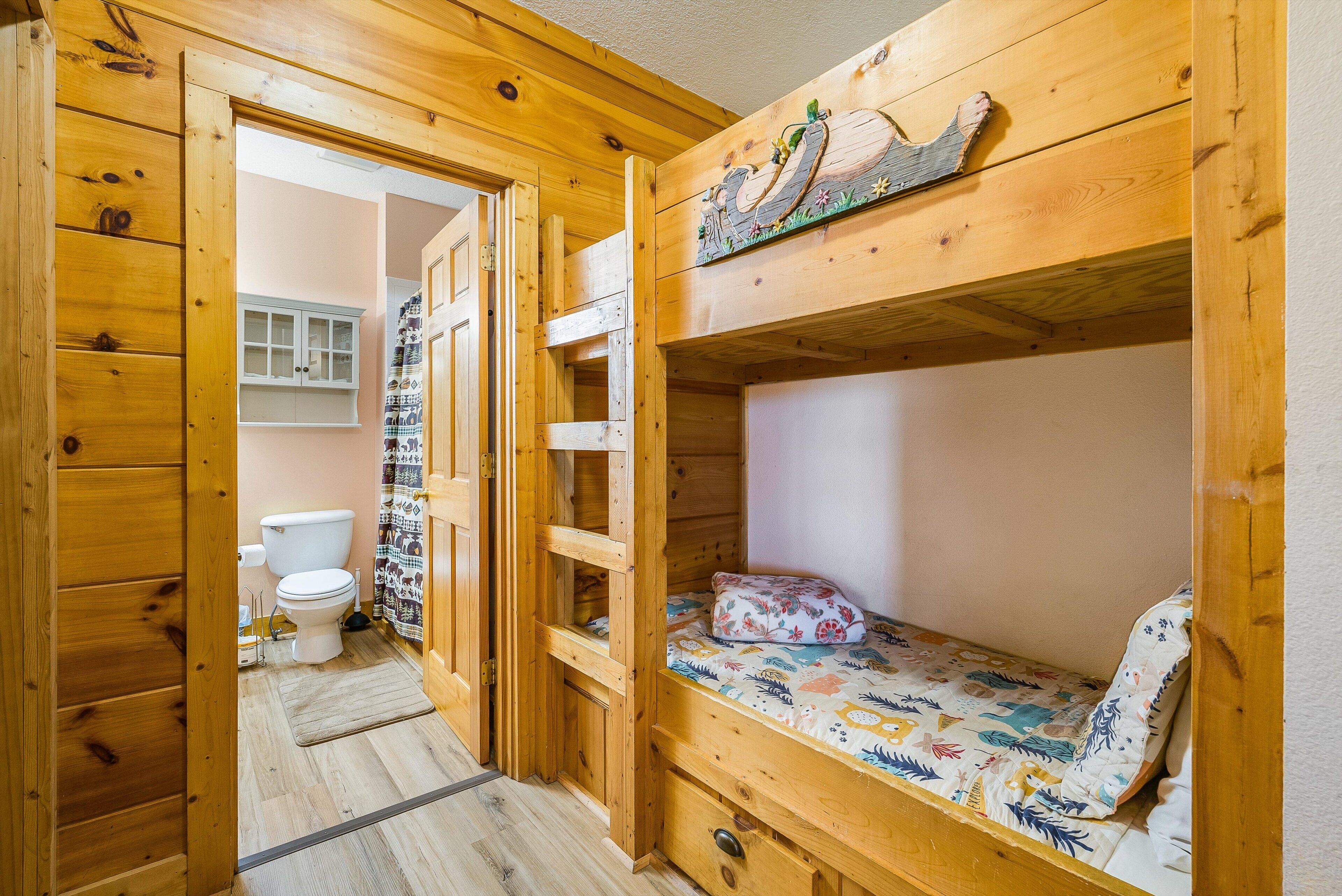 A wooden interior with a bunk bed, a toilet, and a cabinet.