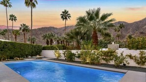 Ein Swimmingpool mit Palmen und Bergen im Hintergrund.