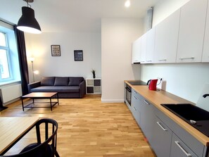 A modern kitchen with grey cabinets, a wooden countertop, and a red kettle.