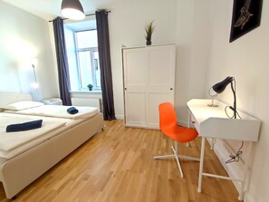 A modern bedroom with a bed, a desk, a chair, a wardrobe, and a window with curtains.
