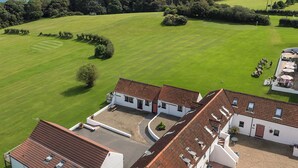 A golf course with a clubhouse and a view of the sea. - Gardener's Cottage - UK6713 (Lydstep, near Tenby)
