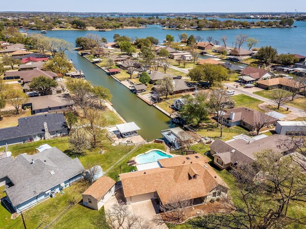An aerial view of a residential area with houses, a river, and a swimming pool.