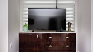 Un televisor de pantalla plana sobre un mueble de madera oscura con tres cajones y dos objetos decorativos encima.