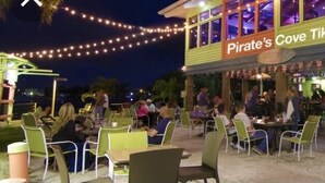 Udendørs siddeområde ved Pirate's Cove Tiki Bar med borde og stole.