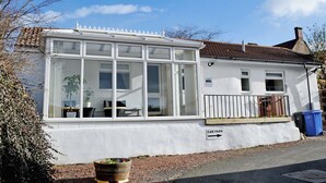 A cottage with a large windowed front, a car park sign, and a small garden area. - 1 bedroom accommodation in Belford near Bamburgh (Belford near Bamburgh)