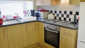 A modern kitchen with wooden cabinets, a gas stove, a built-in oven, and a sink. - 1 bedroom accommodation in Belford near Bamburgh (Belford near Bamburgh)