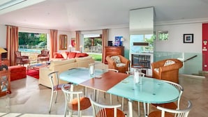 Amplia sala de estar con mesa de vidrio, asientos cómodos, un sofá y vistas al exterior.