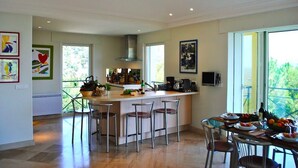 Una cocina moderna con una isla central, taburetes de bar y un comedor con una mesa dispuesta para dos personas.