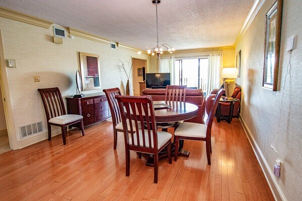 A dining area with a round table and chairs, a television, and a sofa.