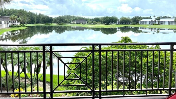 A view of a lake with buildings and greenery. - Lake & Golf Views in Saddlebrook Resort. 2 bed/2bath (Wesley Chapel)