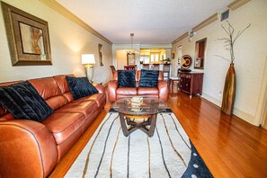 A living room with a brown leather sofa, a glass coffee table, and a patterned rug.