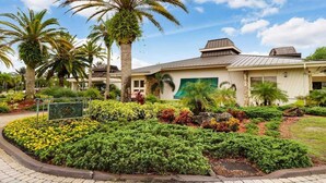 A building with a modern design, surrounded by well-maintained gardens and palm trees. - Lake & Golf Views in Saddlebrook Resort. 2 bed/2bath (Wesley Chapel)