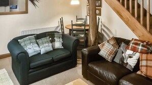 A living room with two sofas, a coffee table, and a staircase. - 2 bedroom accommodation in Melmerby (Melmerby)