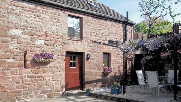 A stone building with a red door, windows, and hanging flower baskets. - 2 bedroom accommodation in Melmerby (Melmerby)