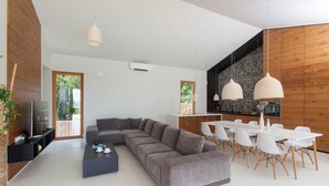 A modern living room with a grey sectional sofa, a black coffee table, and a dining area with white chairs and a white table. - Awarded Design Villa Olea, Luxury Villa with heated pool & Seaview (Klimno (Krk))