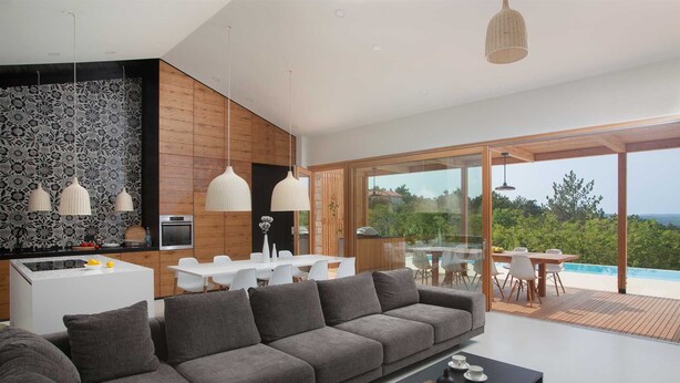 A modern living room with a grey sofa, a dining area with white chairs, and a kitchen with a patterned backsplash. - Awarded Design Villa Olea, Luxury Villa with heated pool & Seaview (Klimno (Krk))