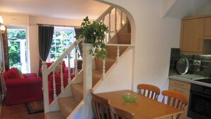 A home interior with a staircase leading to a dining area, a kitchen with a stove, and a living room with a red sofa. - 2 bedroom accommodation in Troutbeck Bridge (Troutbeck Bridge)