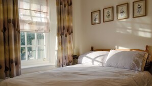 A neatly made bed with white linens in a room with a window and curtains. - 2 bedroom accommodation in Troutbeck Bridge (Troutbeck Bridge)