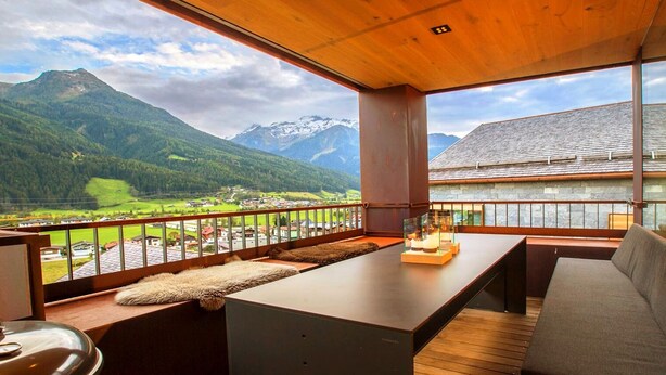 A modern room with a wooden ceiling, a large window overlooking a mountainous landscape, a sofa, and a small table with a glass enclosure. - Delicious dining with a view of Hohe Tauern National Park,close to the ski lift (Bramberg am Wildkogel)