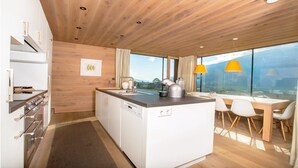 A modern kitchen with a wooden ceiling, a central island, and a dining area with a view. - Delicious dining with a view of Hohe Tauern National Park,close to the ski lift (Bramberg am Wildkogel)