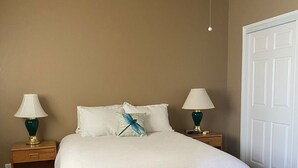 A bedroom with a bed, two bedside tables, a ceiling fan, and a door. - Condo in a Riverfront Complex (Bullhead City)