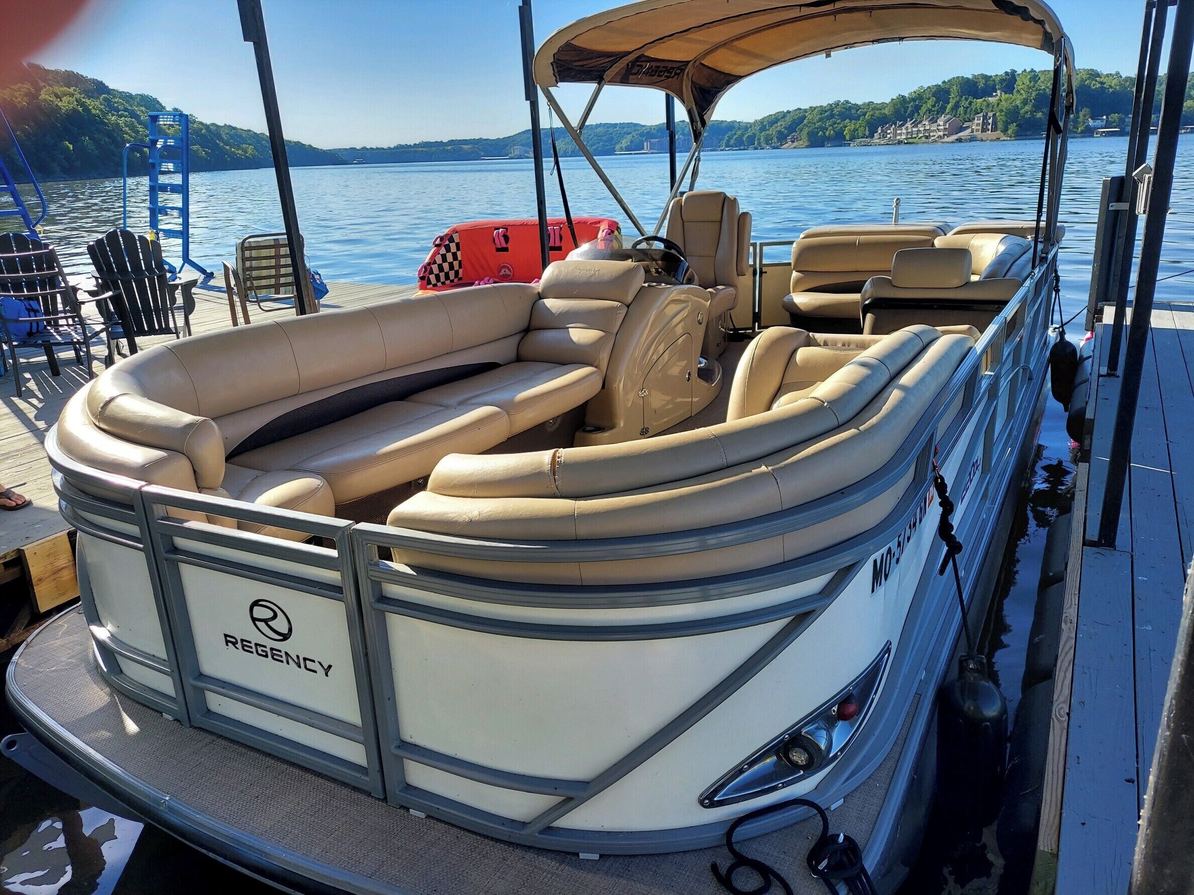 Un barco con zona de estar cubierta, timón y el nombre de marca 'REGENCEY' en el costado.