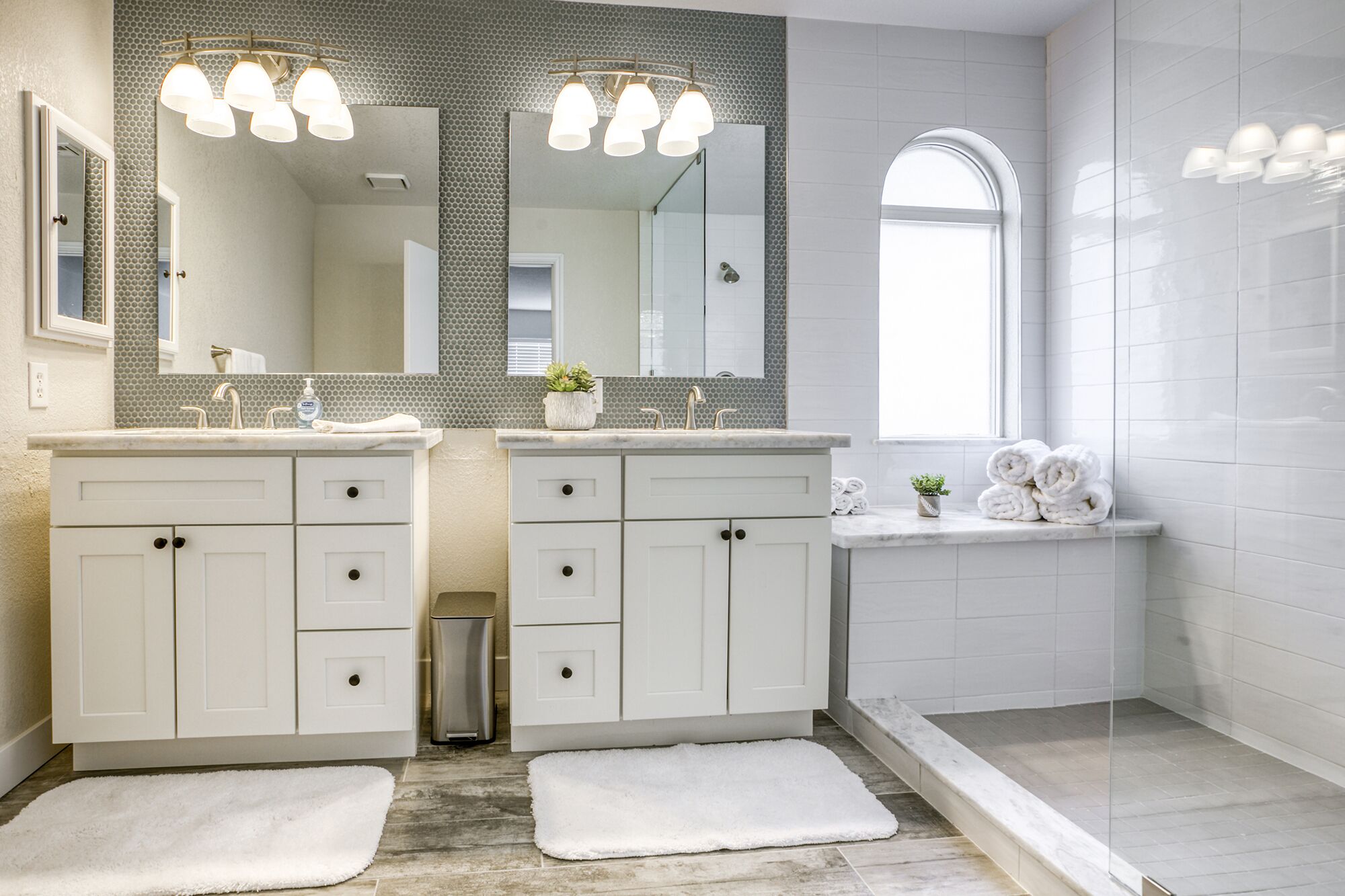 A modern bathroom with two sinks, a large mirror, and a shower area.