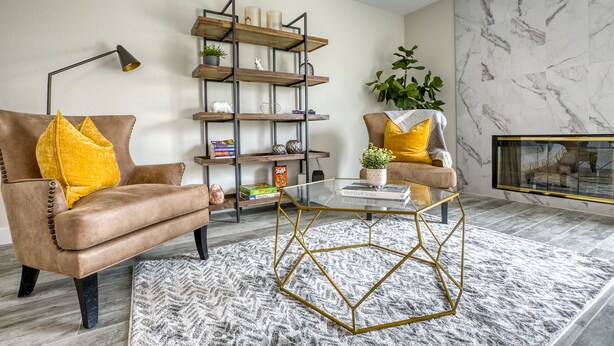 A living room with a leather armchair, a glass coffee table, a wooden bookshelf, and a marble wall. - Modern, Fully Renovated 4 Bedroom House (Las Vegas)