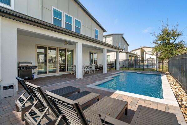 A modern house with a swimming pool, outdoor furniture, and a barbecue area.