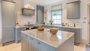 A modern kitchen with grey cabinets, a central island, and a window providing natural light.