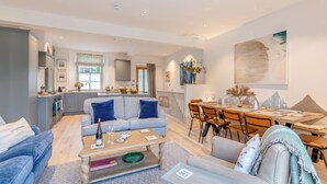 A spacious living area with a sofa, coffee table, and dining table set up for a meal.