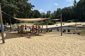 Une plage de sable avec des structures en bois et une piscine.