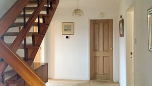 Una escalera que conduce a un rellano con una puerta de madera y un cuadro en la pared.