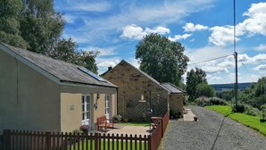 Propiedad rural con camino de grava, cerca de madera y edificios de piedra con jardín.